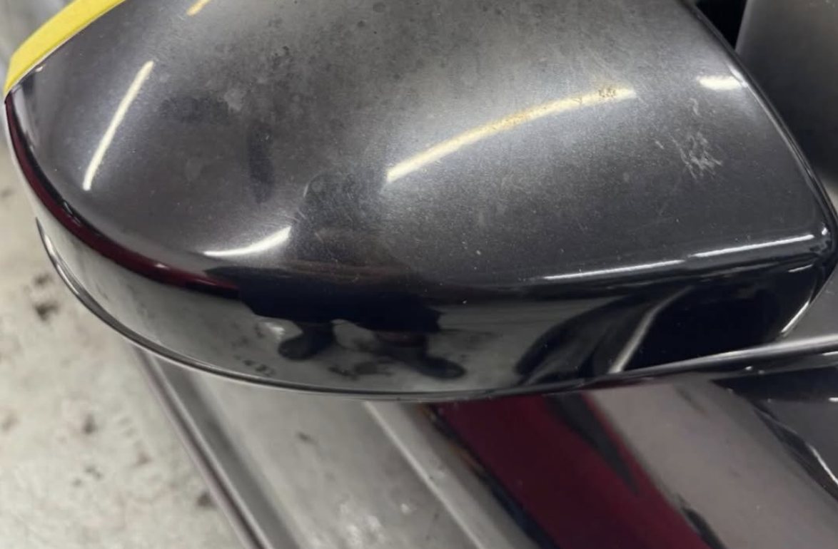 Black wing mirror before paint correction — swirls and haze visible